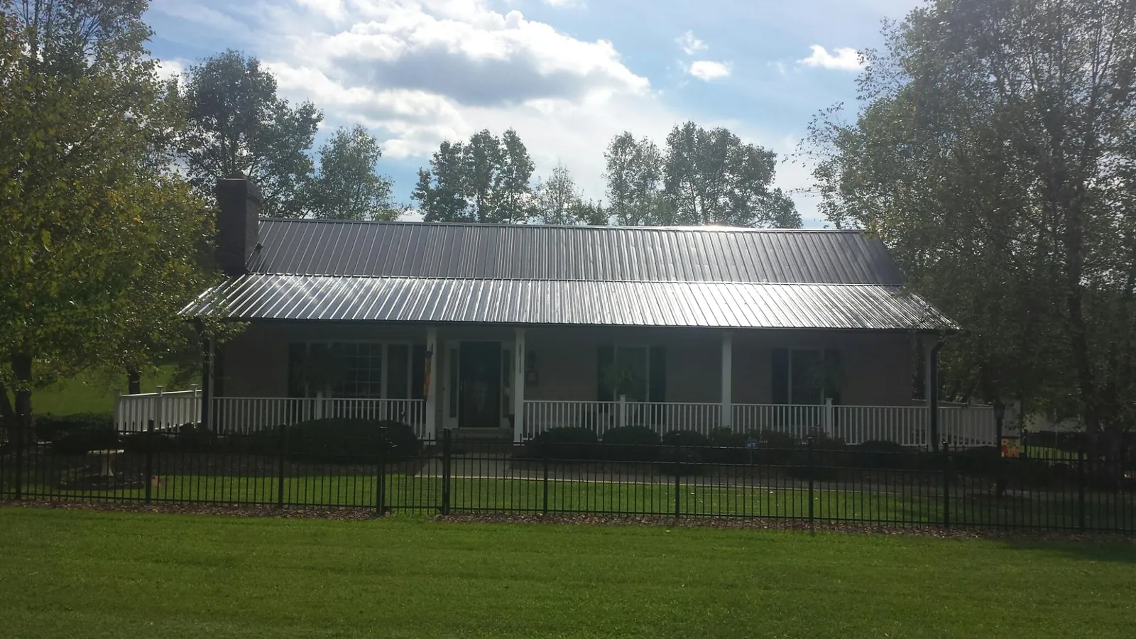 Gray metal roof on a brick ranch with a full width front porch — Gutter Guard Installation work by our crew in Waterloo